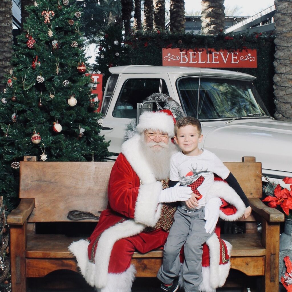 Child sitting on Santa's lap, in front of a truck at Scottsdale Quarter.