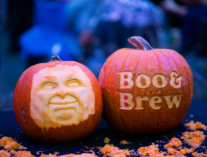 two pumpkins one with a carved face and one carved boo & brew