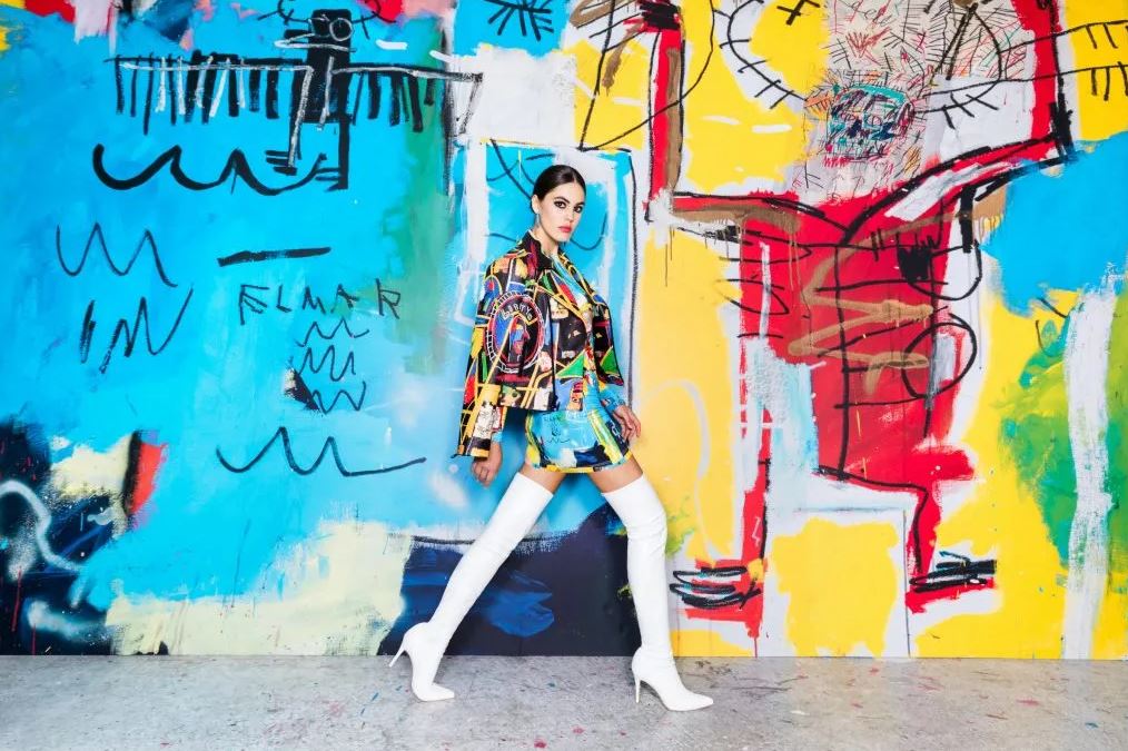 lady wearing the ao basquiat line from alice + olivia in front of a colorful wall
