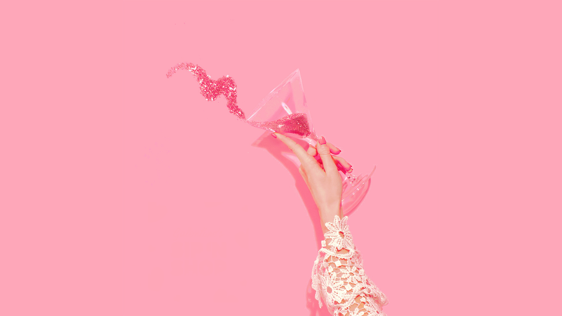 woman holding glass with pink glitter spilling out