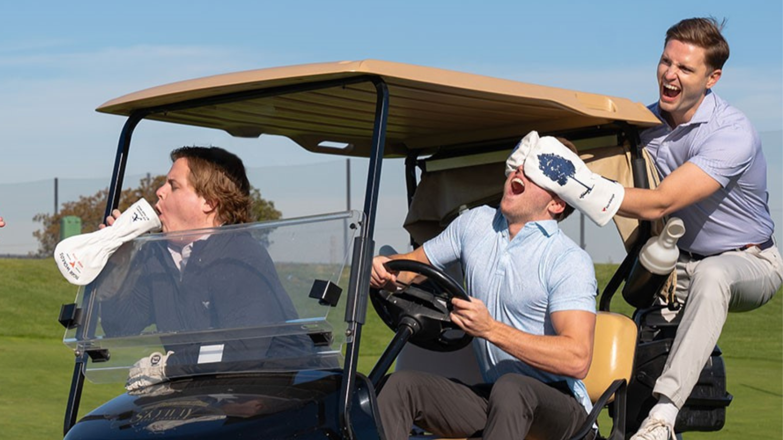 Three men riding a golf cart, acting silly.