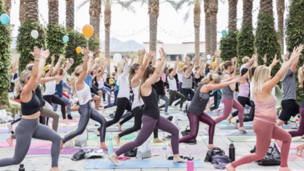 a large group of people working out under palm trees outside