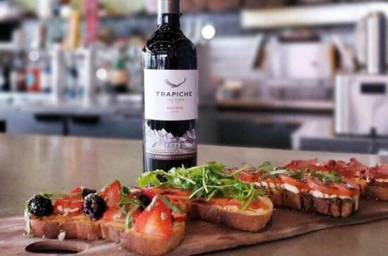 A bruschetta board and a bottle of red wine on a bar top at Sorso Wine Room
