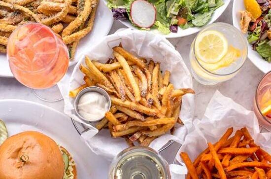 Top view of a table filled with French fries, burgers, salad, and drinks