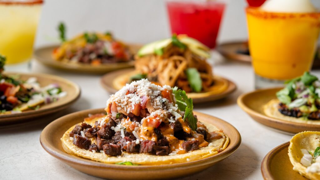 A table with assorted tacos and colorful drinks