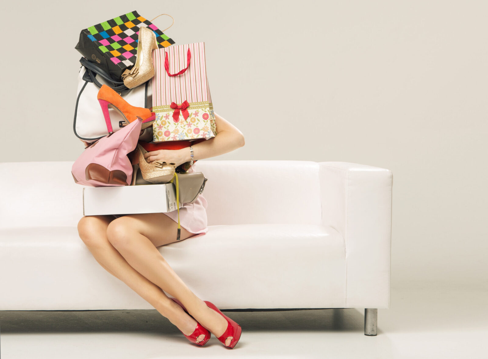 Woman sitting on a couch with shopping bags stacked up