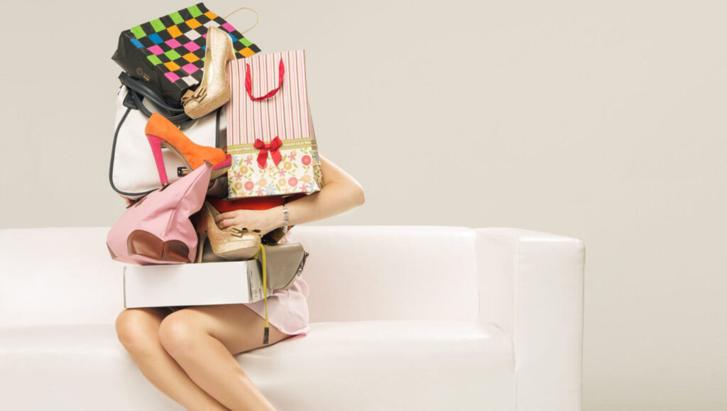 Woman sitting on a couch with shopping bags stacked up