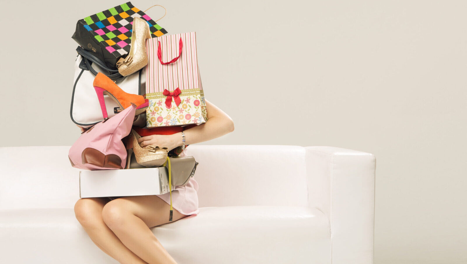 Woman sitting on a couch with shopping bags stacked up