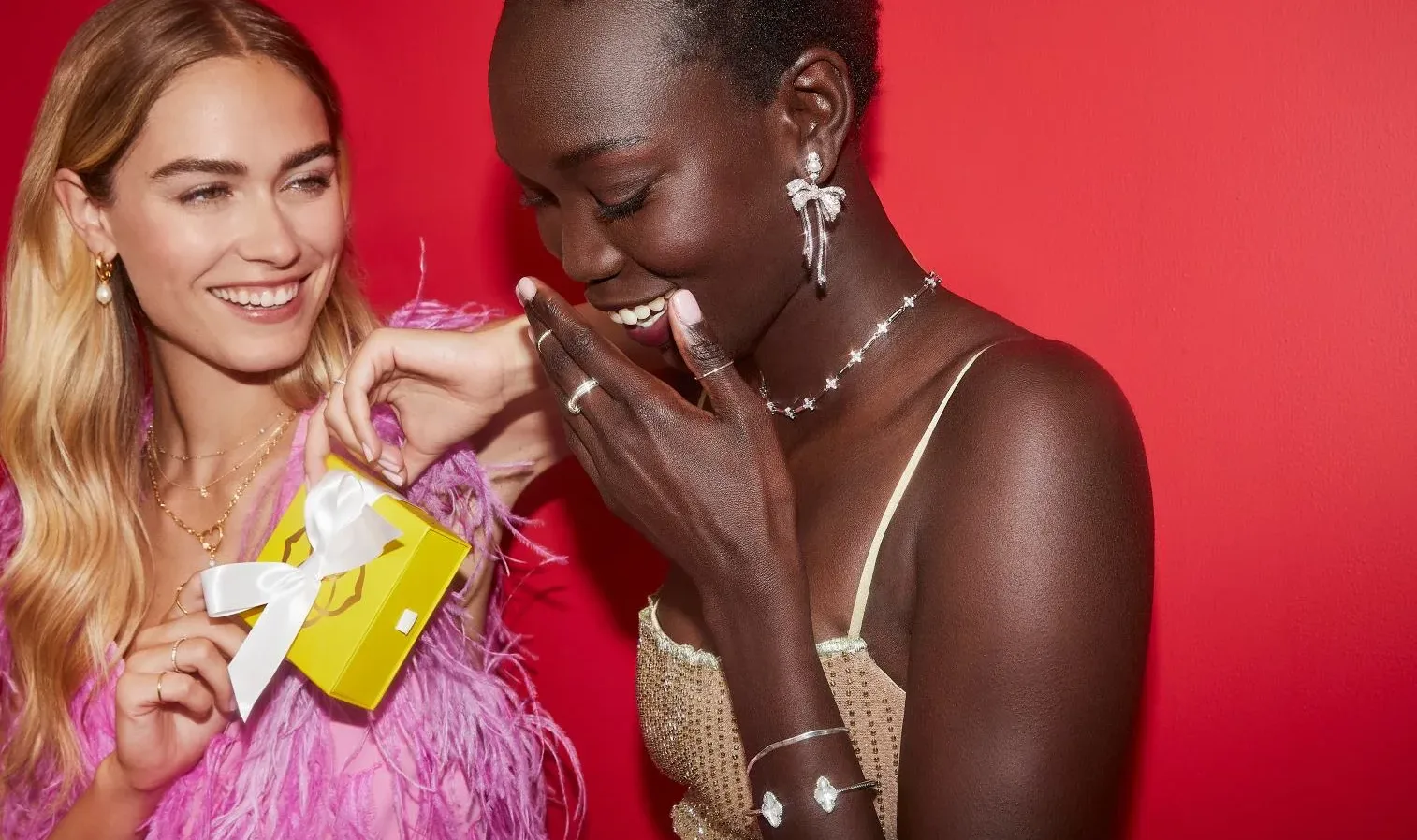 Two women laughing and holding a yellow gift box.