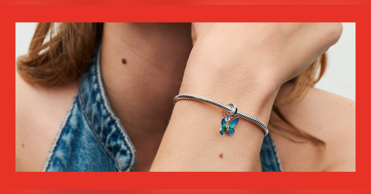 close up view of a wrist wearing a charm bracelet.