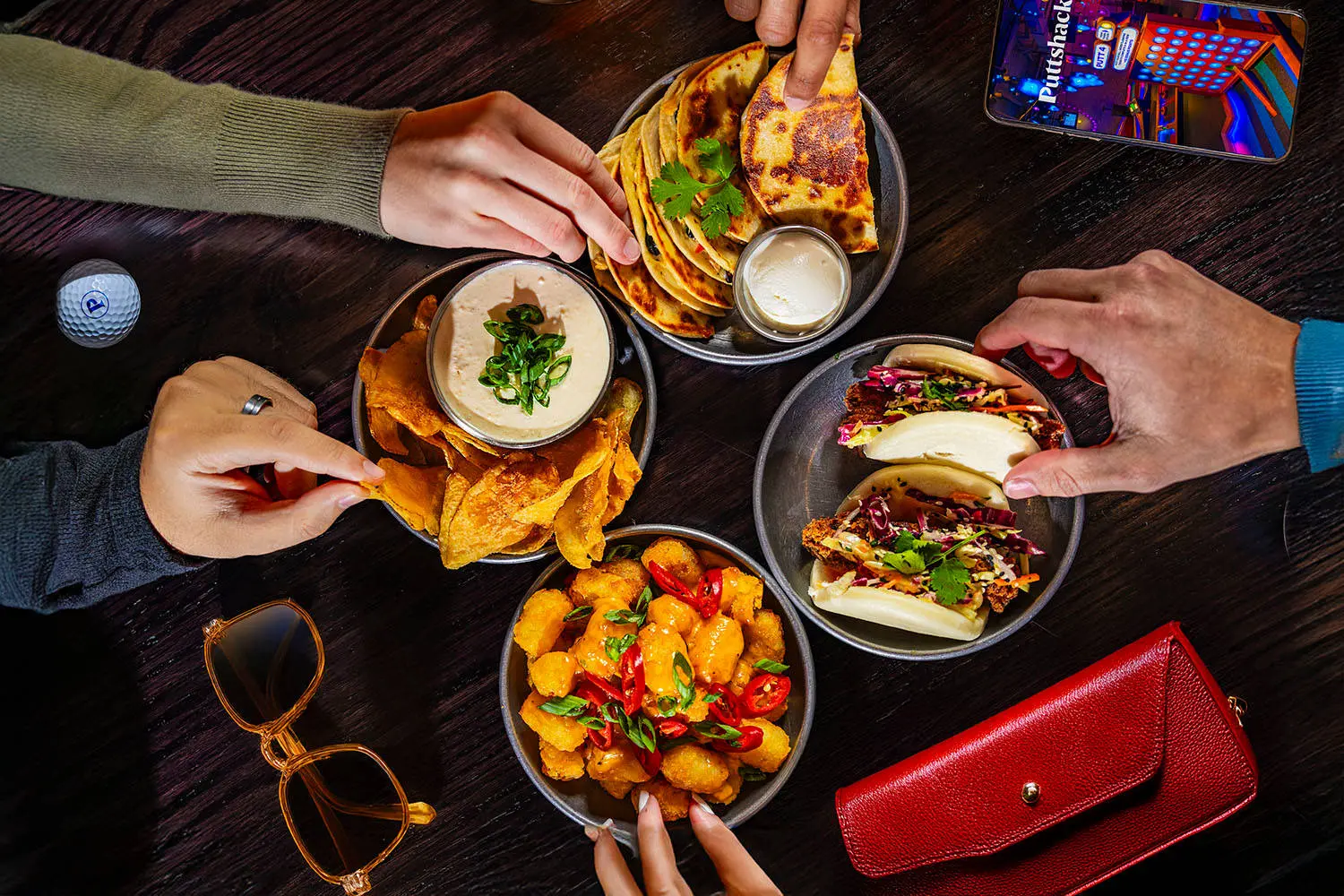 Hands reaching for appetizers on a table