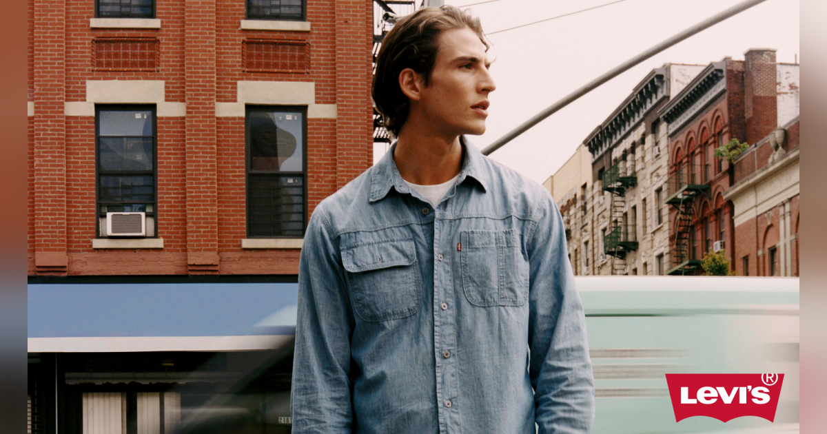 A man in a denim shirt standing on a street