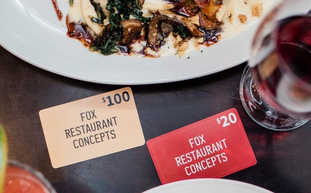 A table with gift cards, plates, and drinks