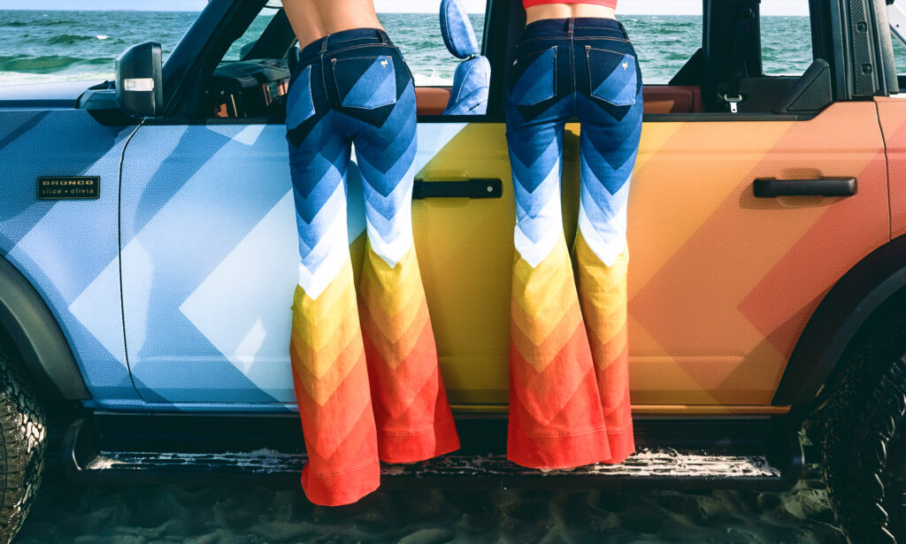 People in colorful denim leaning on a Bronco.