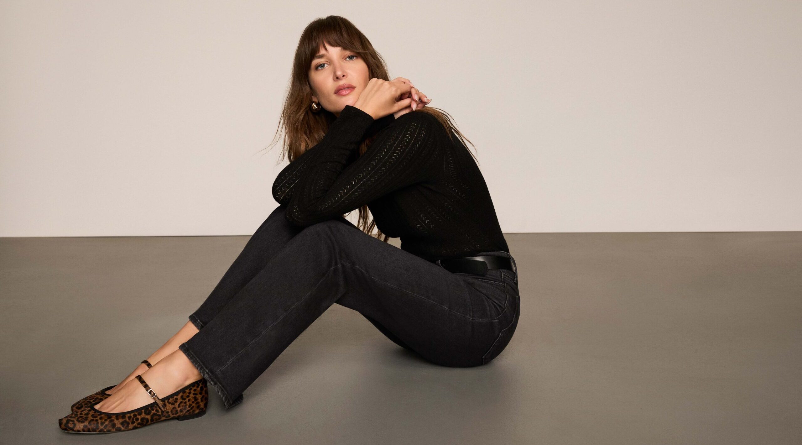 A woman sitting on the ground in fall clothing