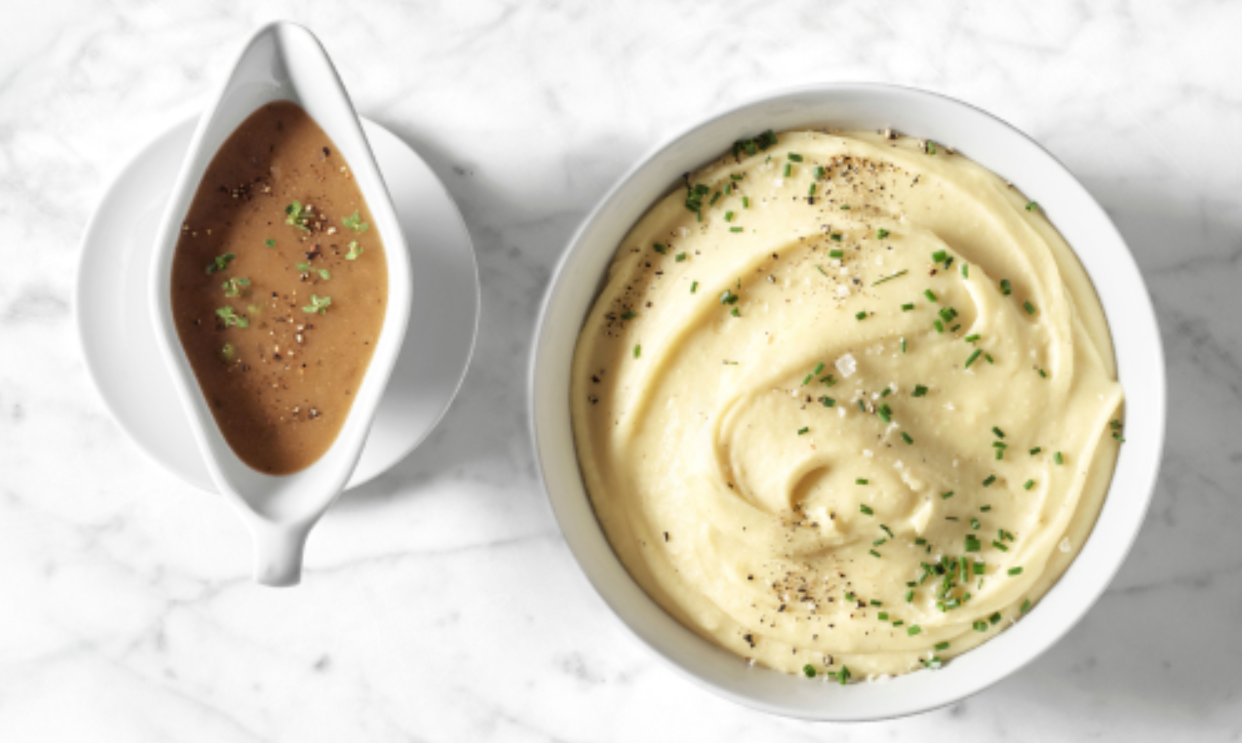 A gravy boat and a bowl of mashed potatoes