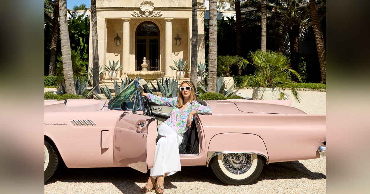 A woman standing next to a pink car