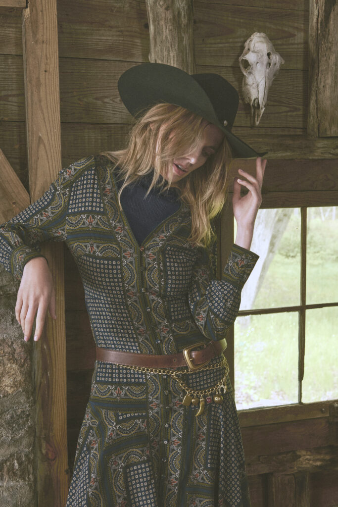 a woman in a dress, tipping her cowboy hat